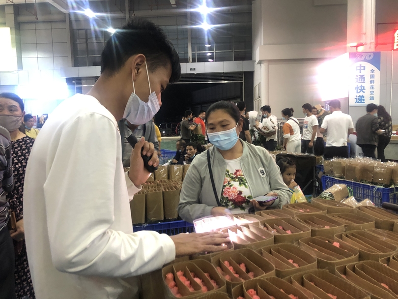หมู่บ้านเล็กๆของคุนหมิง กลายเป็นเมืองแห่งดอกไม้ระดับเอเชีย_fororder_一位广州经销商一边拿起手电筒查看花头的新鲜度、有无病虫害，一边询价。