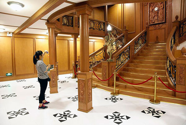 A visitor takes photos in front of a replica stairway at an exhibition displaying cultural relics retrieved from the sunk vessel of Titanic in Guangzhou, Guangdong province, June 16, 2017. [Photo/Xinhua]