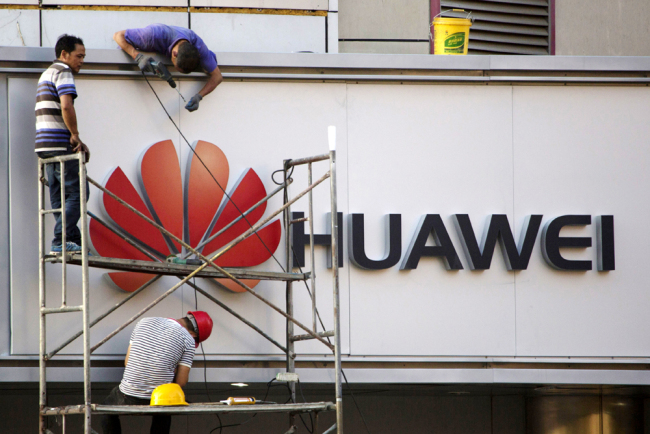 Workers fix panels near the logo for Huawei in Beijing on May 31, 2017. [Photo: AP]