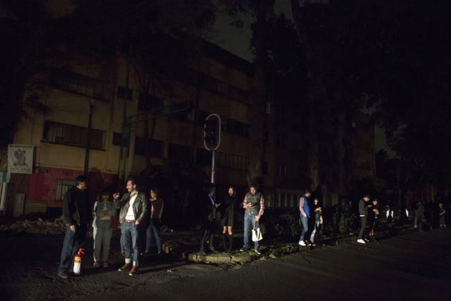 People who evacuated from bars during an earthquake stand in the street in La Roma neighborhood of Mexico City, sections of which lost power, just before midnight on Thursday, Sept. 7, 2017. [Photo: AP/Rebecca Blackwell]