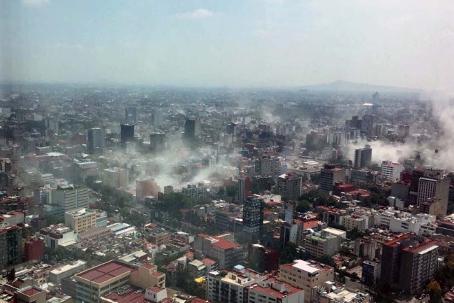 In this photo provided by Francisco Caballero Gout, shot through a window of the iconic Torre Latina, dust rises over down town Mexico City during a 7.1 earthquake, Tuesday, Sept. 19, 2017. Throughout the capital, rescuer workers and residents dug through the rubble of collapsed buildings seeking survivors. [Photo: AP]