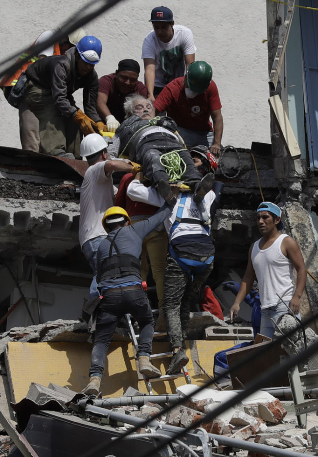 An injured man is pulled out of a building that collapsed during an earthquake in the Roma Norte neighborhood of Mexico City, Tuesday, Sept. 19, 2017. A powerful earthquake jolted central Mexico on Tuesday, causing buildings to sway sickeningly in the capital on the anniversary of a 1985 quake that did major damage. [Photo: AP/Rebecca Blackwell]