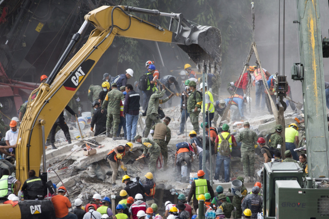 Rescue personnel work on a collapsed building, a day after a devastating 7.1 earthquake, in the Del Valle neighborhood of Mexico City, Wednesday, September 20, 2107. Efforts continue at the scenes of dozens of collapsed buildings, where firefighters, police, soldiers and civilians continue their search to reach the living. [Photo: AP/Moises Castillo]
