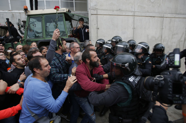 Civil guards clear people away from the entrance of a sports center, assigned to be a referendum polling station by the Catalan government in Sant Julia de Ramis, near Girona, Spain, Sunday, Oct. 1, 2017.[Photo: AP]