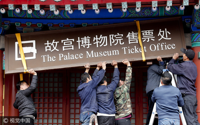 Workers take down a sign at the Palace Museum's ticket office in Beijing on Tuesday. [Photo: VCG]