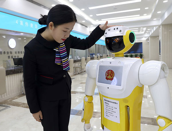 A staff member interacts with Xiaofa, a robot that provides simple legal advice and guidance for litigants, at Beijing No 1 Intermediate People's Court on Thursday. [Photo:China Daily/Zou Hong]