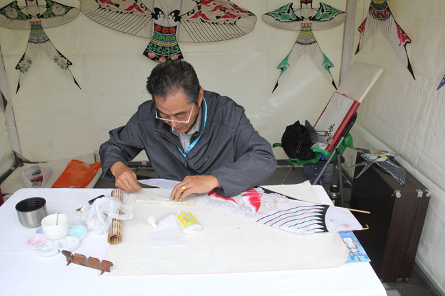 Kite making inheritor makes a kite in Beijing Foreign Language Festival in Beijing Chaoyang Park on Sunday, October 16, 2016. [Photo: China Plus /Ding Xiaoxiao]