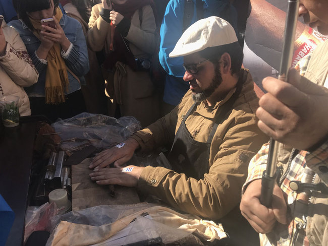 A man shows how Cuban Cigars are made at the "International Charity Sale for Healthy Villages in Yunnan," on October 29, 2017. [Photo: China Plus] 