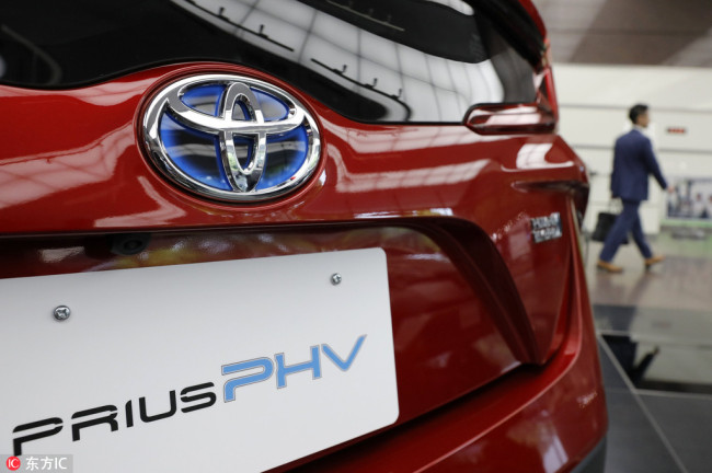 A visitor walks past a Prius Plugin Hybrid car displayed at the company's headquarters in Tokyo, Japan, May 10, 2017. [Photo: IC]
