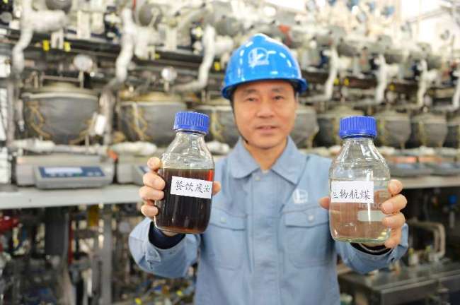 A Sinopec engineer displays a bottle of biofuel (right) next to a bottle of waste kitchen oil. [Photo: Sinopec provided to China Plus]