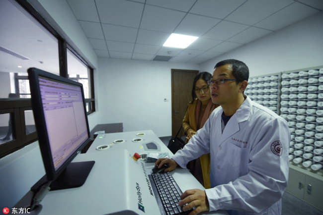 A Traditional Chinese Medicine (TCM) physician dispenses medicine with the help of an artificial intelligence (AI) diagnosis system in Wuzhen, Zhejiang Province on November 25, 2017. Instead of traditional wooden medicine cupboards, he stands in front of high-tech white "pots" which can automatically prepare convenient traditional medicines within 10 minutes. [Photo: IC]