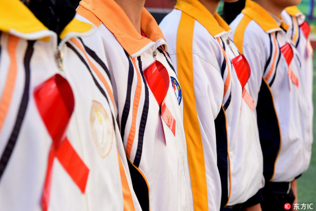 Students from a primary school in Shijiazhuang, Hebei Province wear red ribbons to attend an AIDS prevention activity on November 30, 2017. [Photo: IC]
