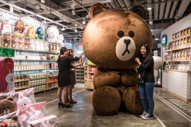 A customer poses with a large stuffed Bear Brown toy at a LINE theme cafe in Shanghai on September 29, 2015. [Photo: IC]