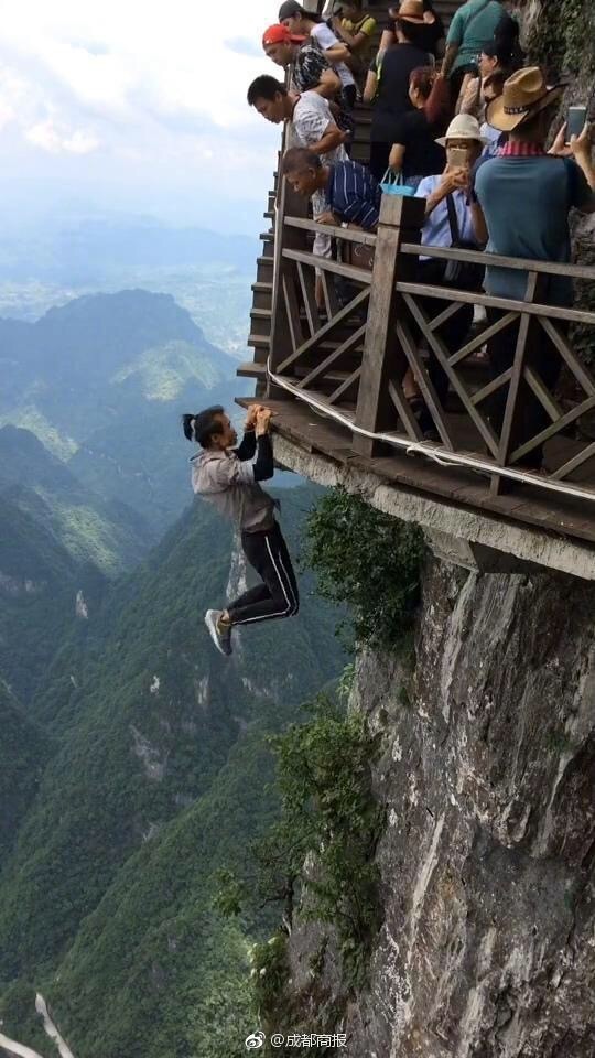Wu hangs on the edge of a skywalk. [Photo: sina.cn]