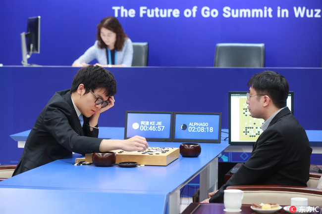 Chinese Go player Ke Jie, left, competes against Google's artificial intelligence (AI) program AlphaGo, as Google DeepMind's lead programmer Aja Huang sits nearby at the second game of the Google DeepMind Challenge Match during the Future of Go Summit on 25 May 2017. [Photo: IC]