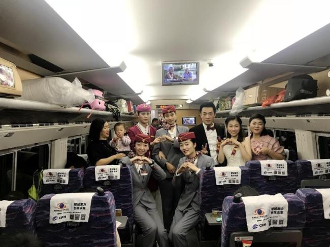 High-speed train staff pose for a photo with a newly married couple on a high-speed train in Guangxi on January 1st, 2018. [Photo: peopleapp.com]