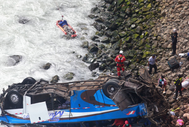 In this photo provided by the government news agency Andina, an injured man is transported over water from a bus that fell off a cliff after it was hit by a tractor-trailer rig, in Pasamayo, Peru, Tuesday, Jan. 2, 2018. [Photo: Andina News Agency via AP/Vidal Tarky]