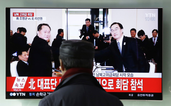 A man watches a TV screen showing South Korean Unification Minister Cho Myoung-gyon, right, shakes hands with the head of North Korean delegation Ri Son Gwon during a meeting, at Seoul Railway Station in Seoul, South Korea, Tuesday, Jan. 9, 2018. [Photo: IC]