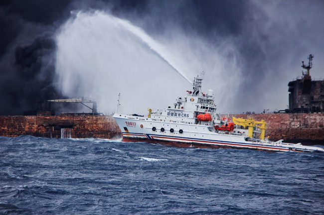 This handout picture taken and released on January 12, 2018 by the Transport Ministry of China shows the Chinese firefighting vessel "Donghaijiu 117" spraying foam on the burning oil tanker SANCHI at sea off the coast of eastern China. [Photo: VCG]