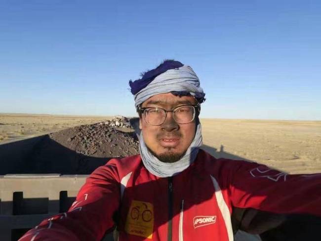 Yuan Jianglei poses for a photo on his 16,000-kilometer ride to come back to his hometown from Africa’s Benin. [Photo: Beijing Youth Daily]