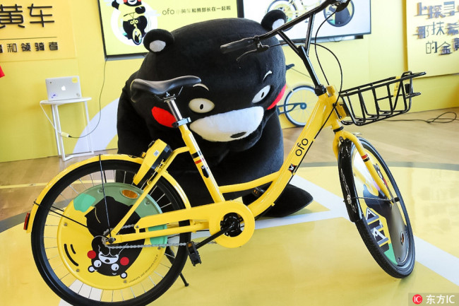 A Chinese employee dressed in the costume of Japan Kumamoto Prefecture's bear mascot "Kumamon" poses with an Ofo bike at Ofo's headquarters in Beijing, January 16, 2018. [Photo: www.dfic.cn]