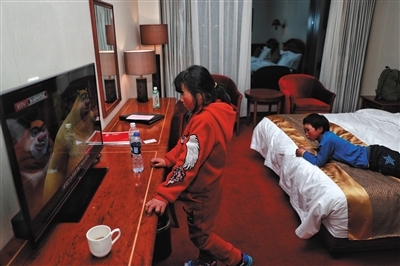 Wang Fuman and his sister watch cartoons on a hotel TV in Beijing on January 19, 2018. [Photo: The Beijing News]