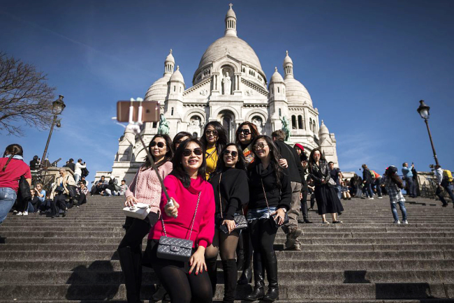 Photo taken on March 30, 2017 shows tourists taking selfie pictures in front of the Sacre Coeur basilica on top of the Paris landmark district of Montmartre in Paris. [Photo: VCG]