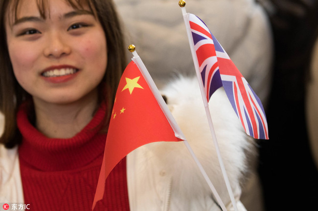 A visitor waves a Chinese flag and a Union flag, also known as a Union Jack, at a youth festival exhibition attended by British Prime Minister Theresa May at Wuhan university in Wuhan, capital of Hubei Province, January 31, 2018. [Photo: IC] 