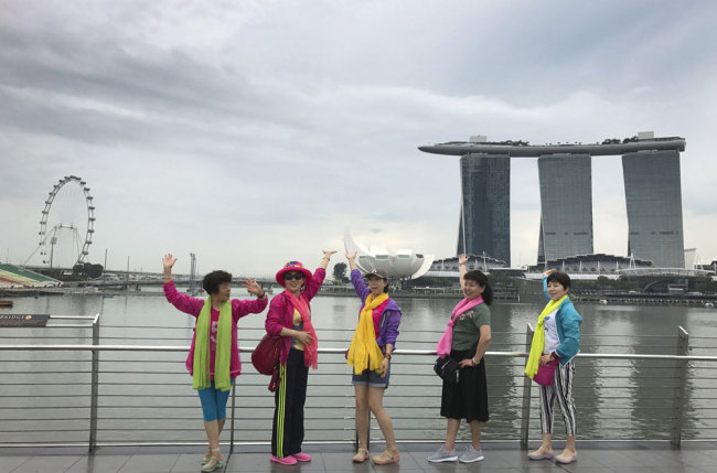 Chinese tourists coordinate their poses as they have their photo taken in front of the Marina Bay area, a popular sightseeing point for visitors in Singapore, Monday, April 3, 2017.[Photo: AP/Wong Maye-E]
