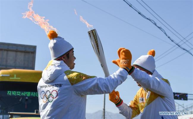 Chinese torch bearer Ding Shizhong (L) participates in the Olympic Torch Relay in Donghae, Gangwon-do province, South Korea, Feb. 6, 2018. The 2018 PyeongChang Olympic Winter Games will kick off here on Feb. 9.[Photo:Xinhua]