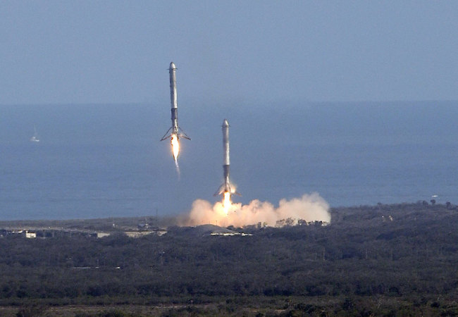 Two booster rockets from the Falcon 9 SpaceX heavy, return for a landing at the Kennedy Space Center in Cape Canaveral, Fla., Tuesday, Feb. 6, 2018.[Photo: AP]