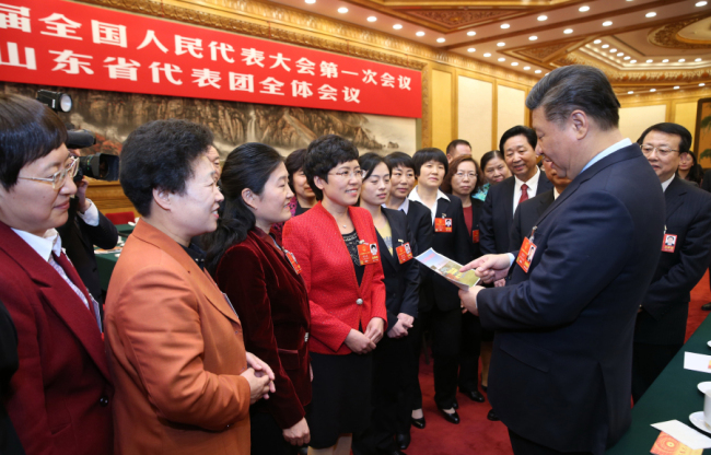 President Xi Jinping looks at a photo showing football training for female high school students while at a panel discussion with deputies from Shandong Province who are in Beijing for the 13th National People's Congress (NPC). [Photo: Xinhua/Yao Dawei]