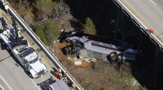 Rescue crews work at the scene of a deadly charter bus crash on Tuesday, March 13, 2018, in Loxley, Ala. The bus carrying Texas high school band members home from Disney World plunged into a ravine before dawn Tuesday. [Photo: AP/Dan Anderson]