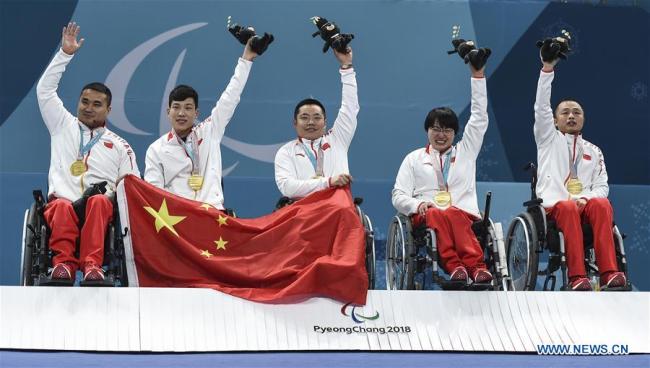 Gold medalists China's Wang Haitao, Chen Jianxin, Liu Wei, Wang Meng and Zhang Qiang (L to R) celebrate on the podium during the awarding ceremony for wheelchair curling at the 2018 PyeongChang Winter Paralympic Games at Gangneung, South Korea, March 17, 2018. China beat Norway in the final 6-5 to claim the title of the event, which is also China's first-ever Winter Paralympic medal with gold. [Photo: Xinhua]