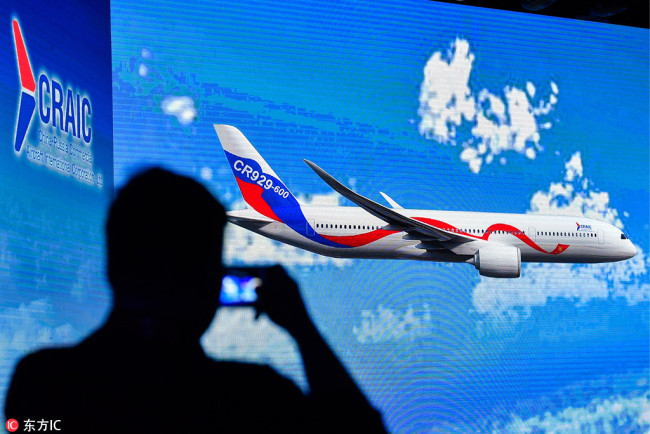 A staff member takes picture of a video screen showing the CR929 wide-body long-range passenger aircraft during a ceremony at the headquarters of the Commercial Aircraft Corporation of China (COMAC) in Shanghai on September 29, 2017. [Photo: IC]