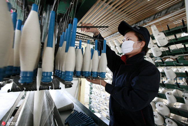 A worker installs spindles of yarn on a spinning machine at a garment factory in Huaibei city, Anhui Province. [File Photo: IC]