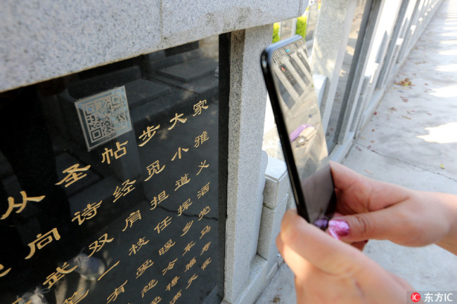 A worshiper scans the QR code on a tombstone to view the profile of the deceased at Guishan Memorial Park in Xiangyang, in central China's Hubei province, on Wednesday, March 28 2017. [File photo: IC]