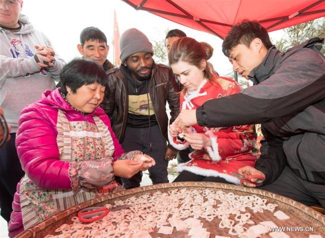 Christina Marie Weige (2nd R) makes Spring Festival snack under instruction of her husband (1st R) and villagers in Gaocun Village of Anji County, east China's Zhejiang Province, Feb. 9, 2018. [Photo: Xinhua]