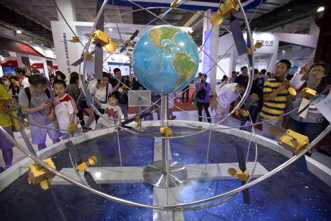 Visitors look at a mockup of China's homegrown Beidou satellite navigation system at the China Beijing International High-Tech Expo in Beijing, Saturday, June 10, 2017. [Photo: AP/Mark Schiefelbein]