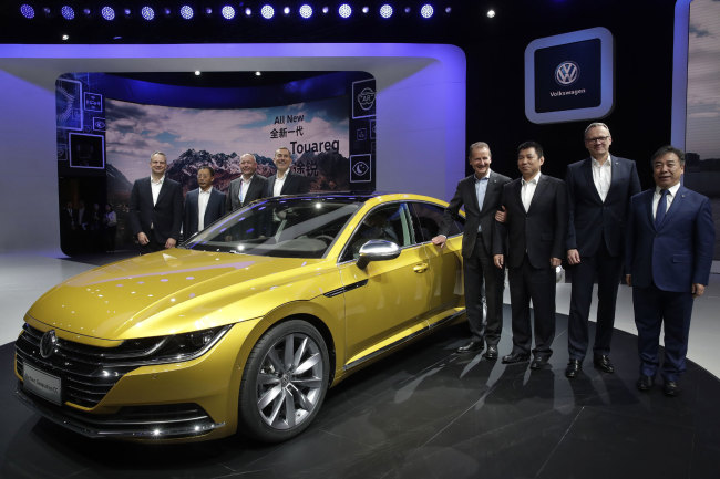 Herbert Diess, CEO of Volkswagen, fourth from right, poses with officials and the newly unveiled Volkswagen CC car model during the media day of the China Auto Show in Beijing, Wednesday, April 25, 2018. Volkswagen and Nissan have unveiled electric cars designed for China at a Beijing auto show that highlights the growing importance of Chinese buyers for a technology seen as a key part of the global industry's future.[Photo:AP]