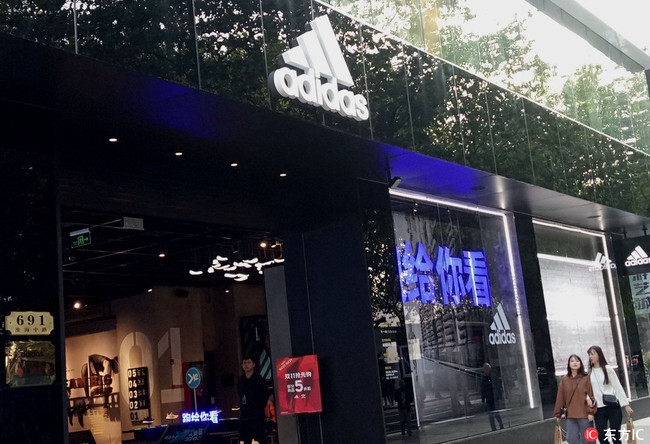 Pedestrians walk past a sportswear store of Adidas in Shanghai October 27, 2017. [File photo: IC]