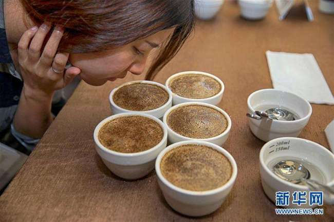 A customer smells coffee at a trade center in Chongqing [File Photo: Xinhua]