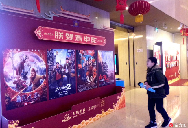A Chinese filmgoer walks past posters for movies at a cinema in Shanghai, March 3, 2018. [File Photo: IC]