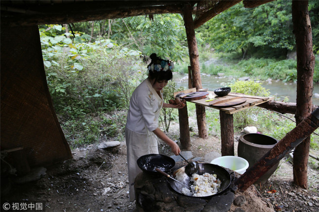 Zhang uses a wood-burning stove to make rice with potatoes, creating a taste of her childhood. [Photo/VCG]