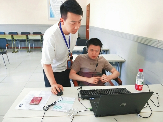 A staff member helps a visually impaired candidate submit his examination paper for social work in Chengdu, capital of Sichuan Province, June 10, 2018. [Photo: West China City Daily]
