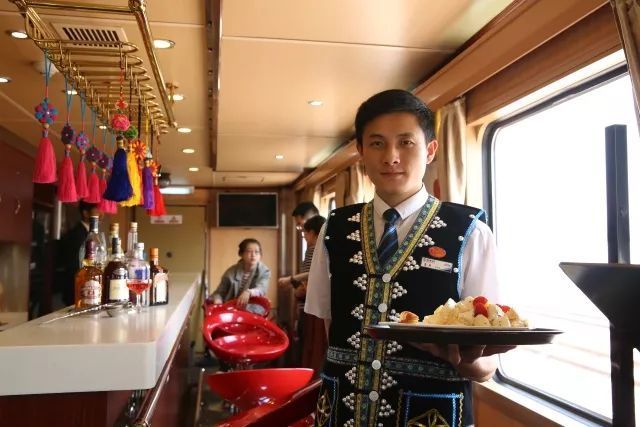 A crew member serves food to passengers on a Kunming-Lijiang tourist train. [Photo: China Railway]
