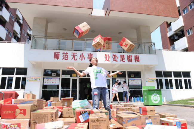 Peng poses with 618 delivery parcels of food, clothing, and daily necessities she received in Nanjing, capital of East China's Jiangsu Province, June 18, 2018. [Photo/IC]