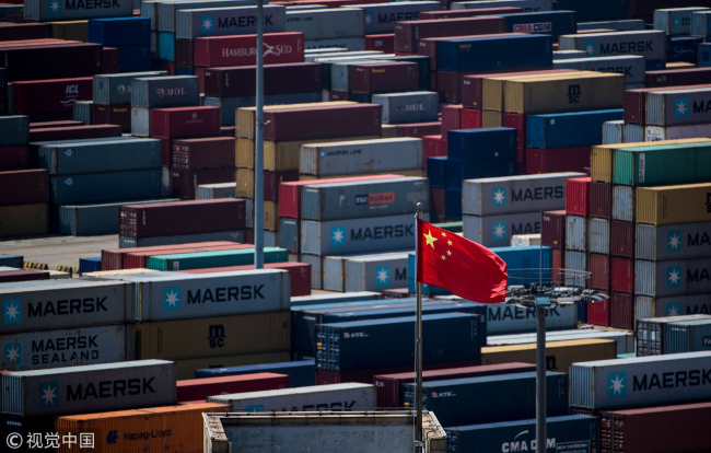 A Chinese flag is seen in front of containers at the Yangshan Deep-Water Port, an automated cargo wharf, in Shanghai, April 9, 2018. [Photo: VCG] 