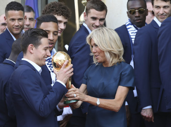 French President Emmanuel Macron's wife Brigitte Macron (C) holds the trophy during a reception at the Elysee Presidential Palace on July 16, 2018 in Paris, after French players won the Russia 2018 World Cup final football match. [Photo: AFP/Ludovic MARIN]