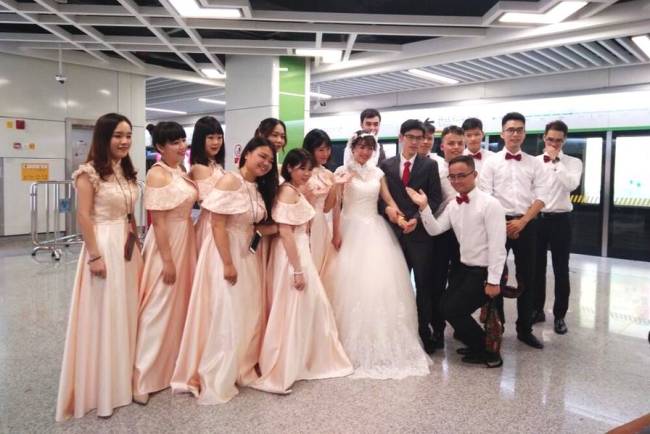 The bride and groom, along with 14 bridesmaids and groomsmen, pose for a group photo at a subway station near the bride's home before heading to their wedding ceremony in Nanning, the capital of Guangxi Province, on Sunday, July 15, 2018. [Photo: ifeng.com]